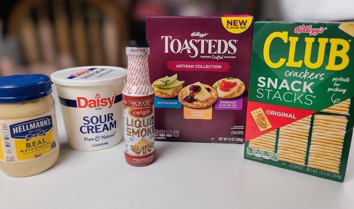 Ingredients for Smoked Tuna Dip on a white counter, mayo, sour cream, crackers and liquid smoke