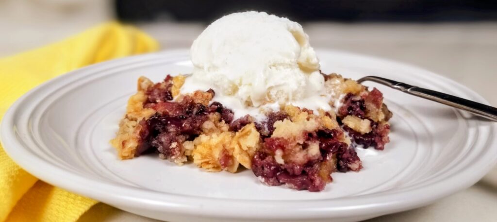 blackberry cobbler dump cake on a plate with vanilla ice cream on top