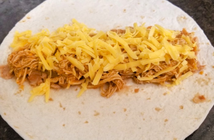 refried beans, shredded chicken, shredded cheddar cheese layered down the middle of an open flour tortilla shell