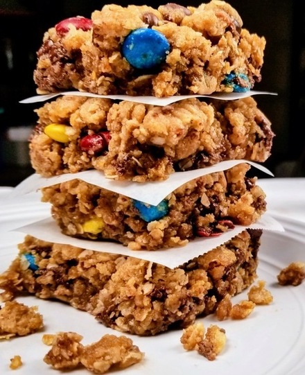 four monster cookie bars stacked on a white plate
