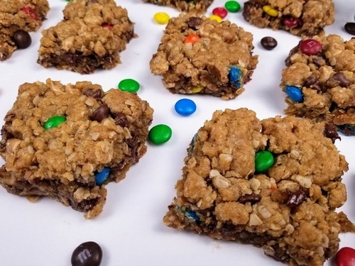 monster cookie bars and M&M's spread out on a white counter