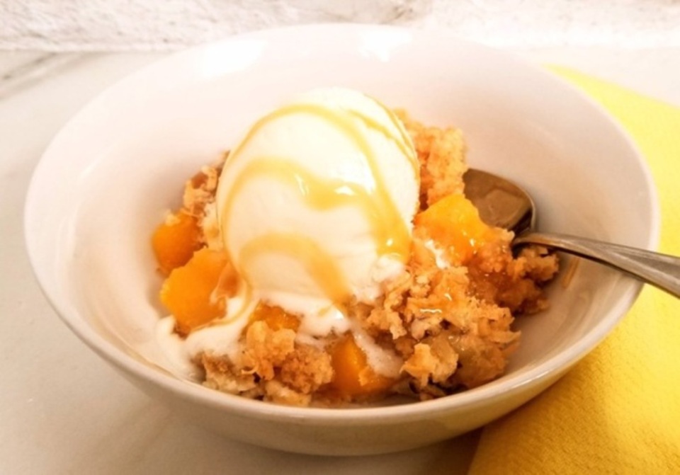 peach cobbler dump cake ina bowl with a scoop of ice cream
