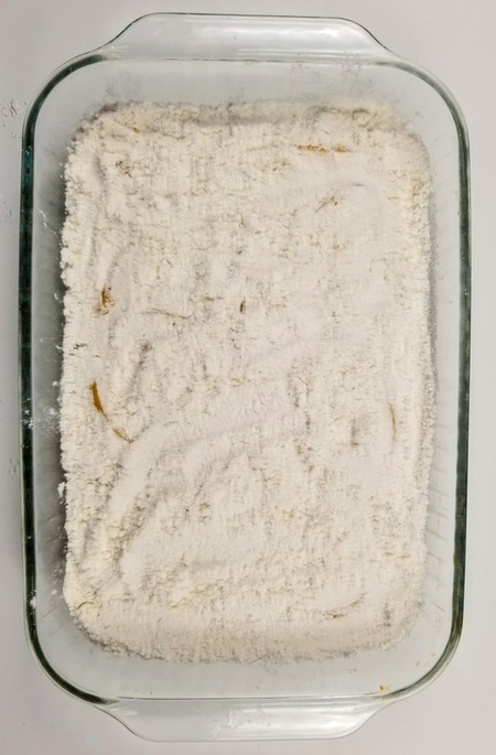 peaches in a cake pan with white cake mix on top