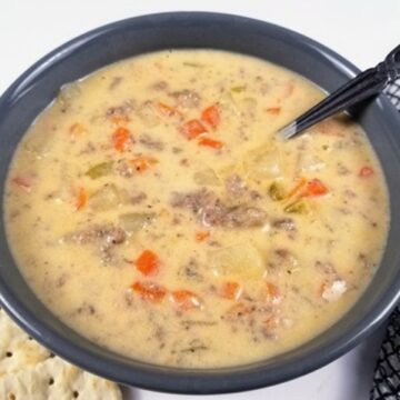 cheeseburger soup in a grey bowl with crackers next to bowl
