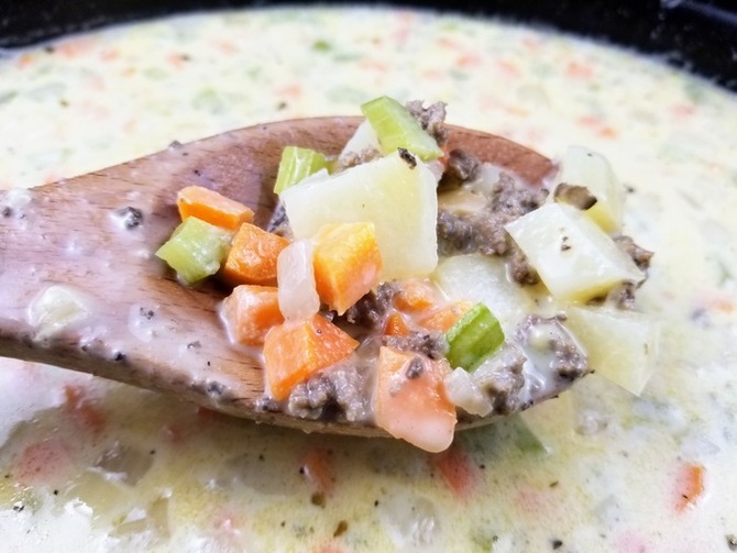 cheeseburger soup in a crock pot with a wooden spoon