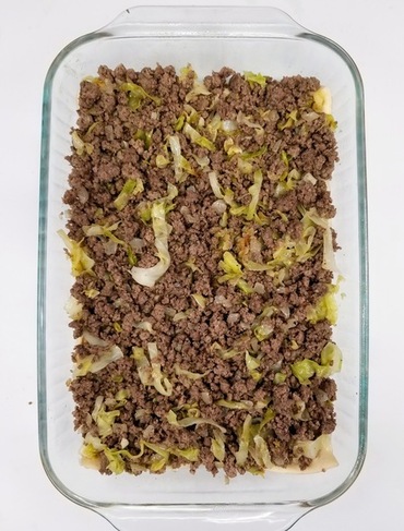 crescent roll dough topped with hamburger mixture in cake pan
