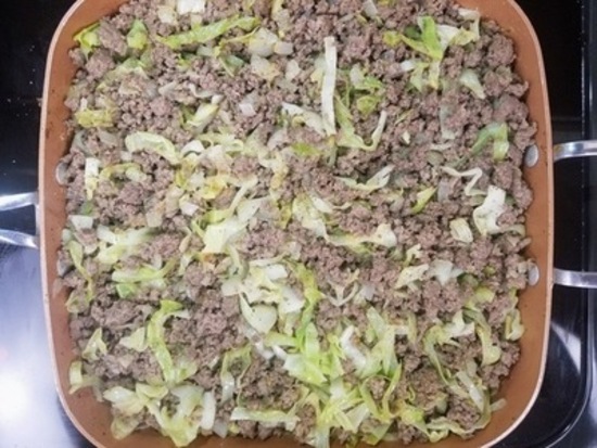 hamburger, onions, and green cabbage cooking in a pan