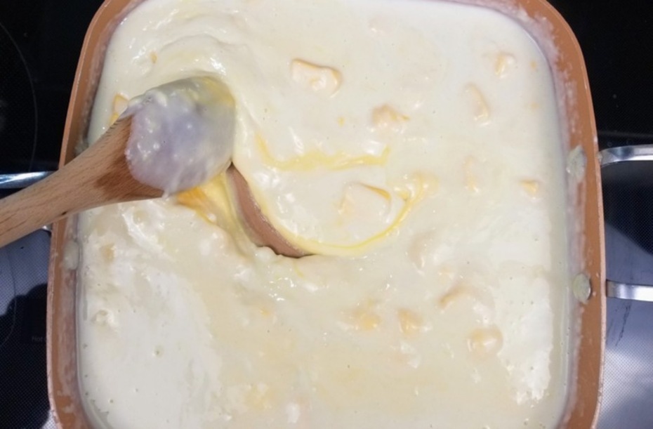 cheese sauce in a pan on a stove being stirred with a wooden spoon for cheeseburger soup recipe