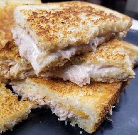 three grilled tuna fish sandwiches stacked on a black plate