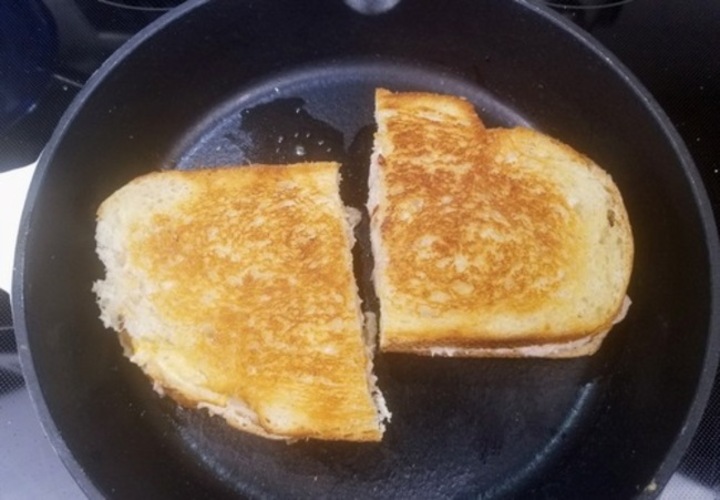 two golden brown grilled tuna sandwiches cooking on a cast iron skillet