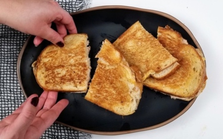 four grilled tuna sandwhiches laying on a large black plate