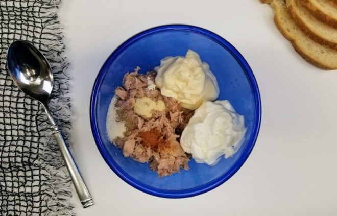 blue bowl with sour cream, mayo, tuna, cayenne, onion powder, and salt and pepper on a white counter