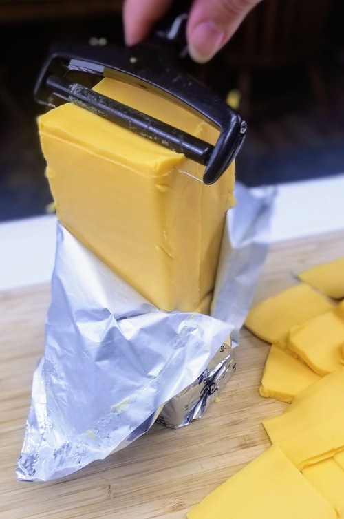 block of velveeta cheese being sliced on a cutting board