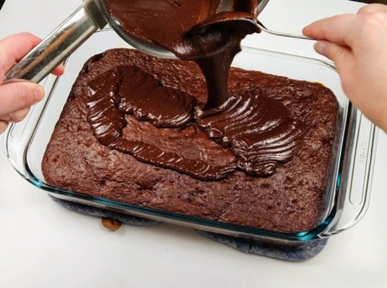 chocolate gnache frosting being poured onto easy cherry chocolate cake