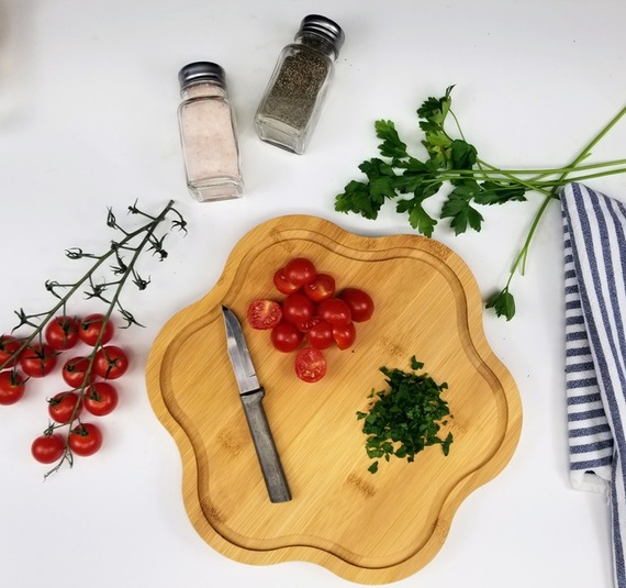 sliced tomatos and parsley on a cutting board next to salt and pepper shakers